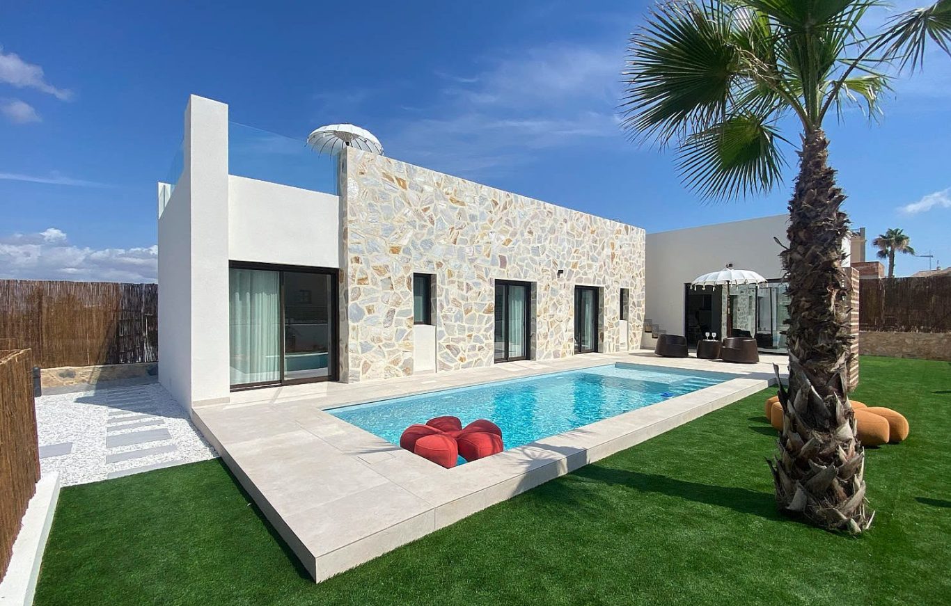 LIEGE Mediterránea Vivienda Piloto Casa moderna con piscina, jardín y palmera, decorada con muebles exteriores.